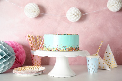 Stand with fresh delicious cake and birthday decorations on table