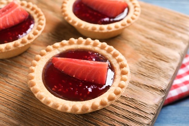 Tasty tartlets with strawberry jam on wooden background