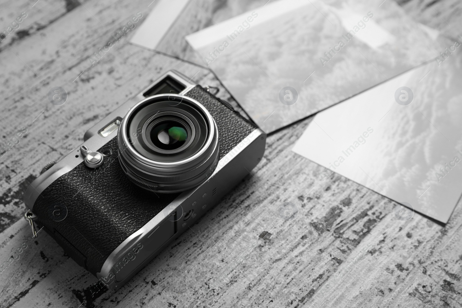 Photo of Vintage photo camera and beautiful printed pictures on rustic table. Creative hobby