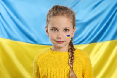 Little girl with face paint near Ukrainian flag
