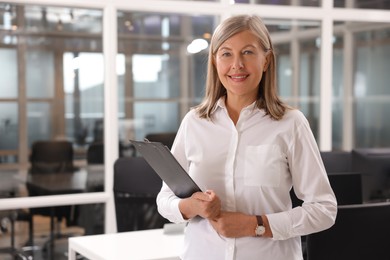 Photo of Smiling woman with clipboard in office, space for text. Lawyer, businesswoman, accountant or manager