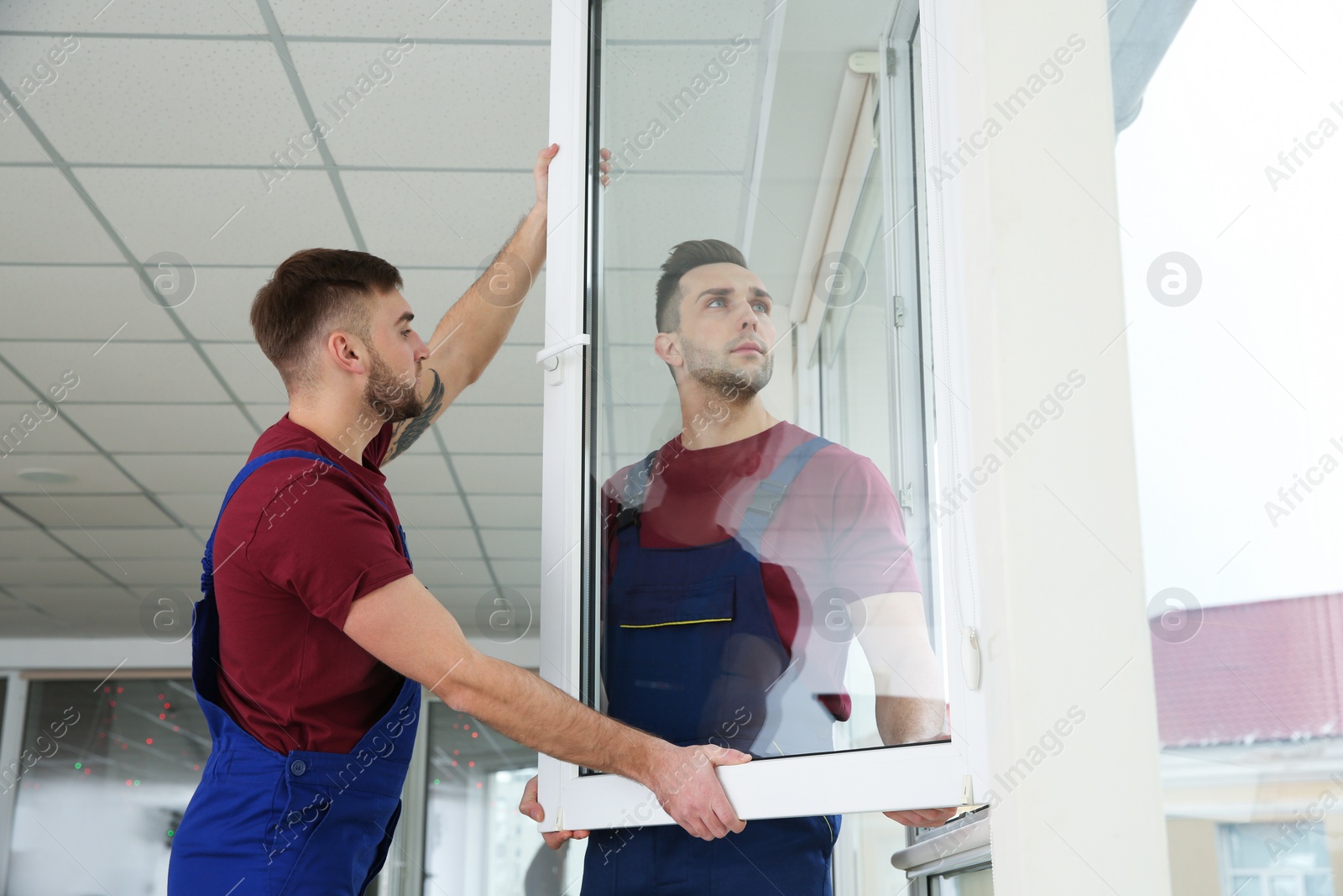 Photo of Construction workers installing plastic window in house