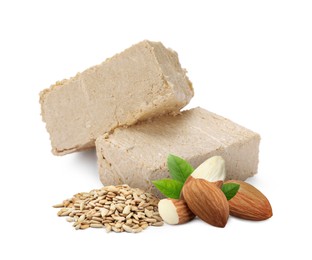 Image of Tasty halva, peeled sunflower seeds, almonds and green leaves isolated on white