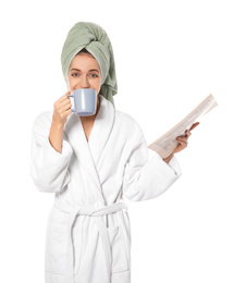 Beautiful young woman in bathrobe reading newspaper on white background