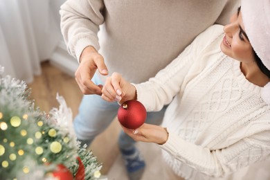 Photo of Happy couple decorating Christmas tree at home