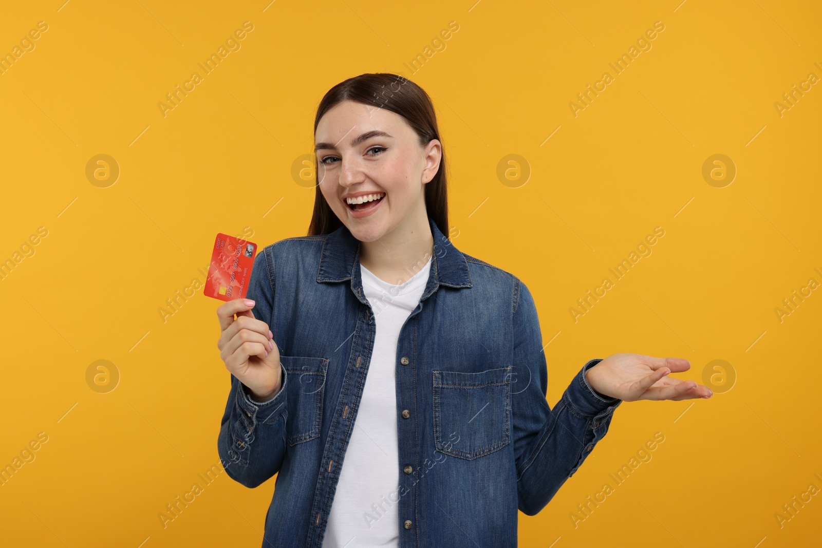 Photo of Happy woman with credit card on orange background