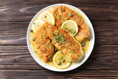 Delicious chicken piccata on wooden table, top view