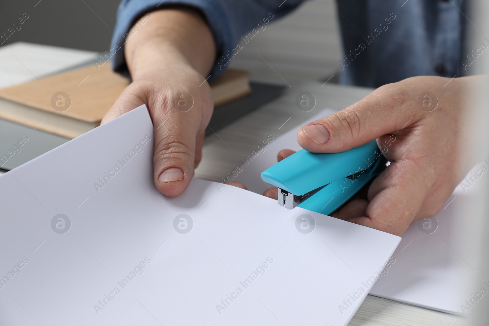 Photo of Man with papers using stapler at table, closeup