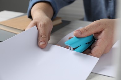 Photo of Man with papers using stapler at table, closeup