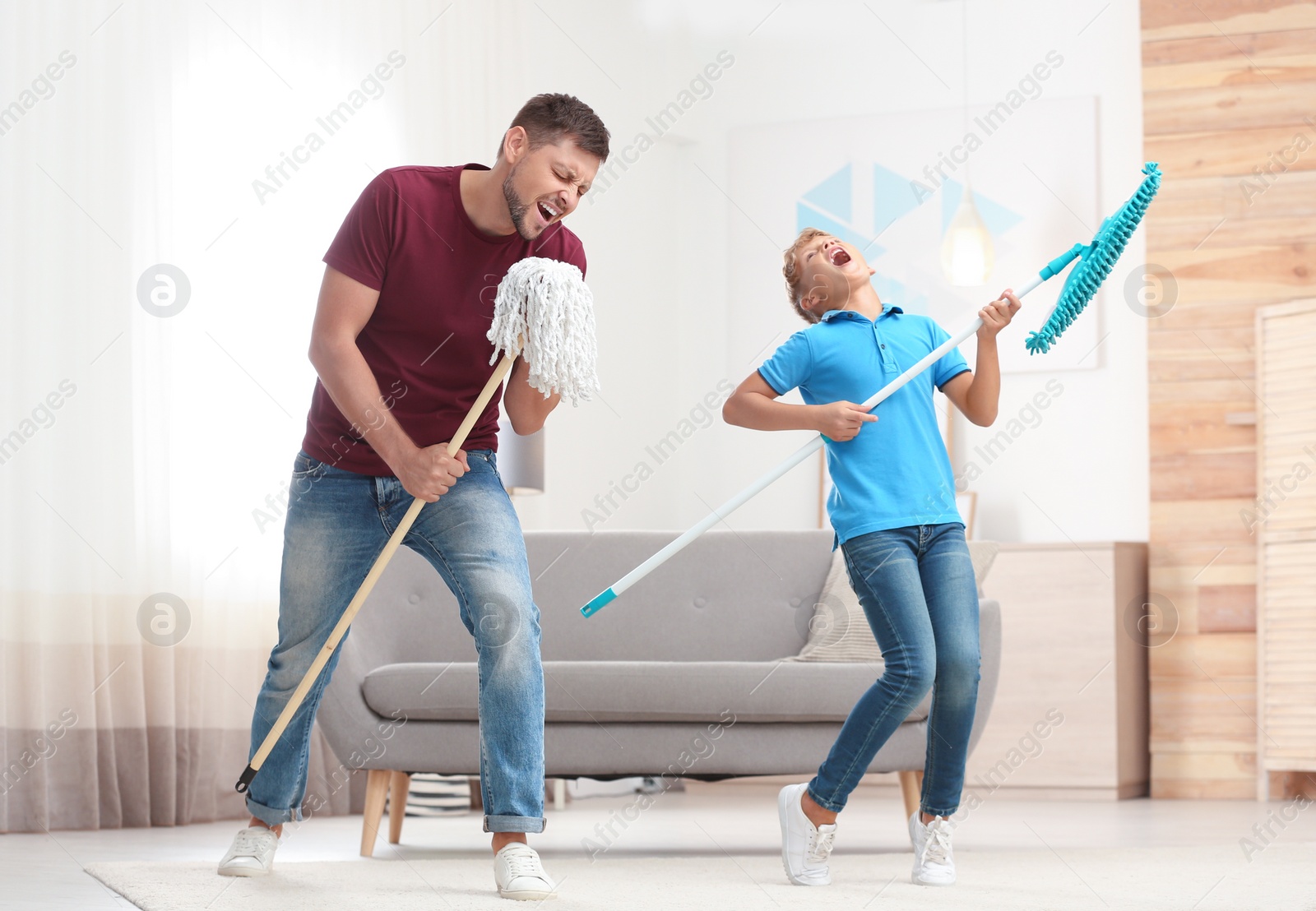 Photo of Dad and son having fun while cleaning living room together