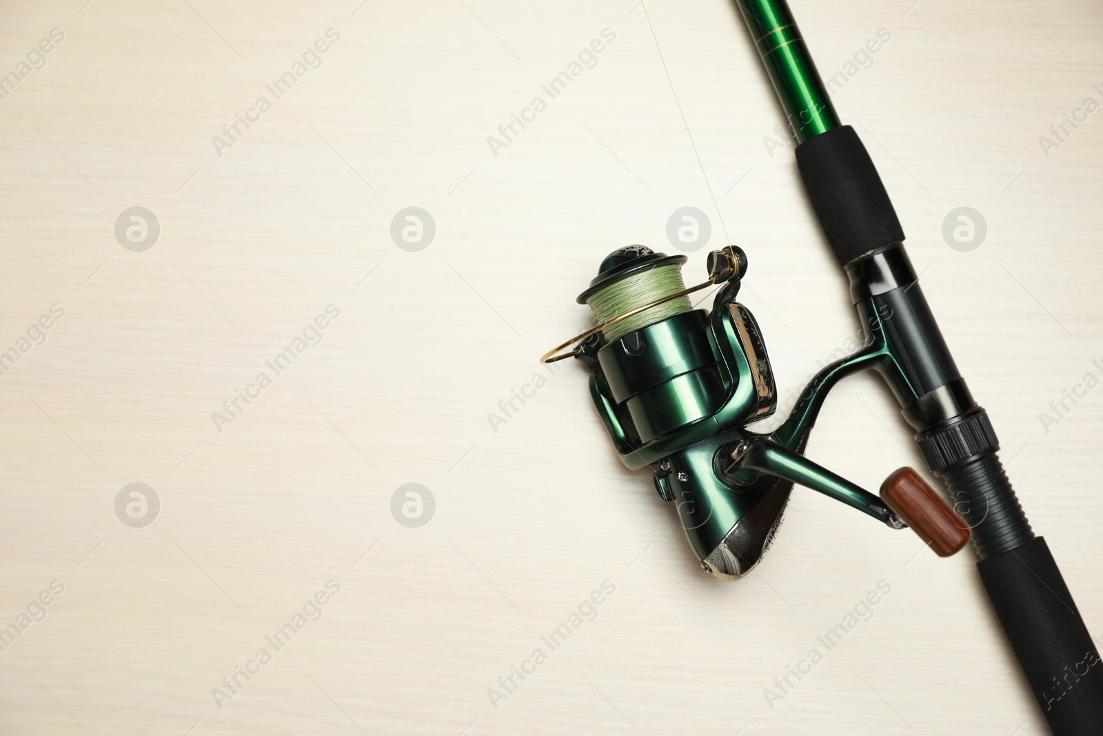 Photo of Modern fishing rod with reel on wooden background, top view. Space for text