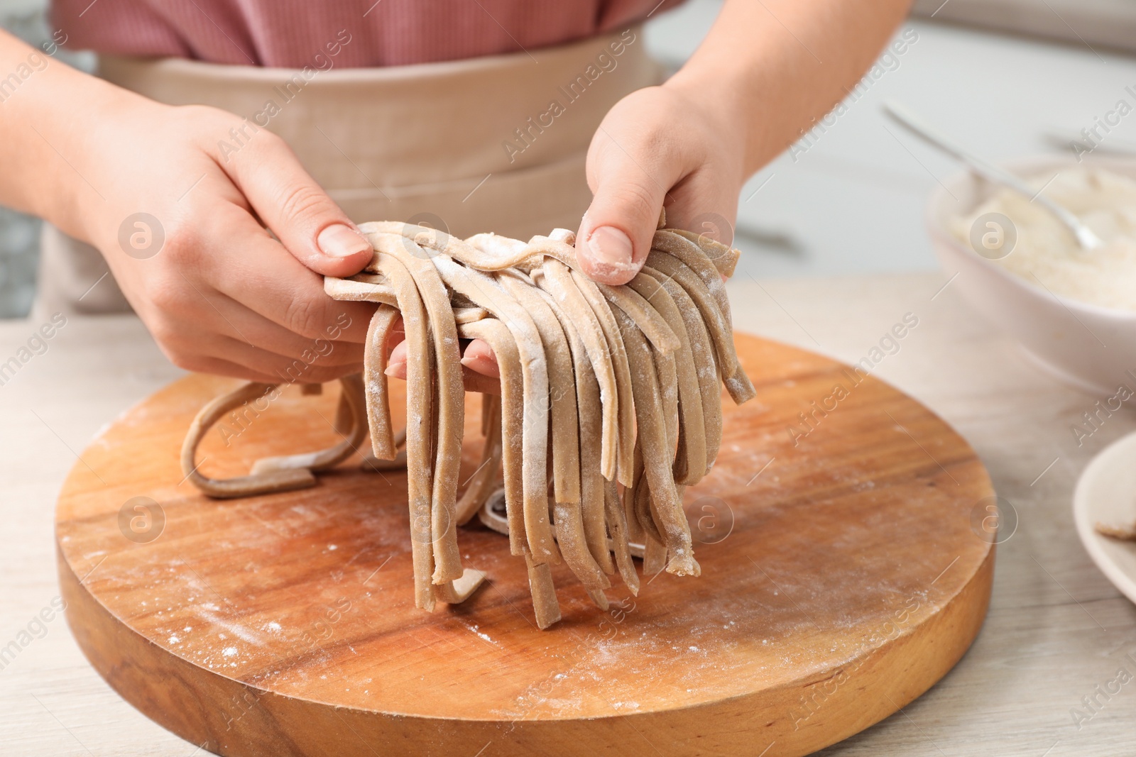 Photo of Woman making soba (buckwheat noodles) at wooden table, closeup