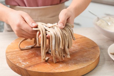 Photo of Woman making soba (buckwheat noodles) at wooden table, closeup