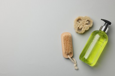 Photo of Liquid soap, brush and luffa on grey background, flat lay. Space for text