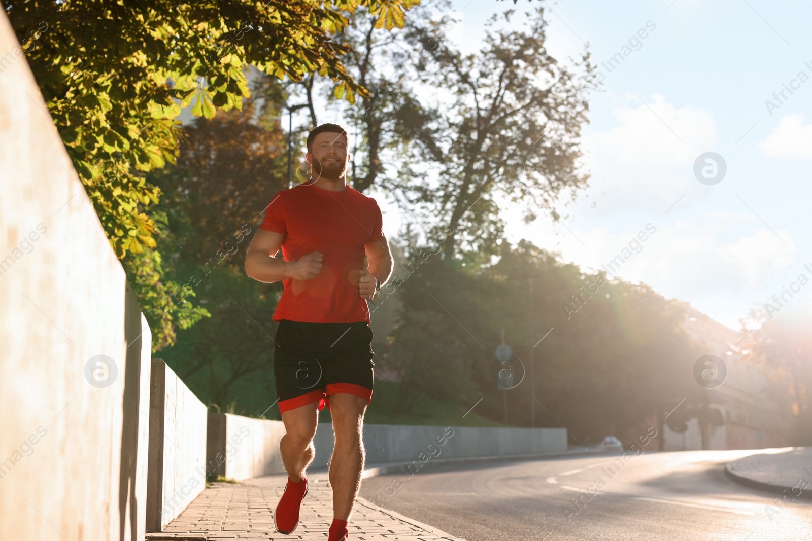 Photo of Happy man running outdoors on sunny day. Space for text