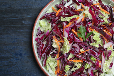 Photo of Fresh cabbage salad served on blue wooden table, top view