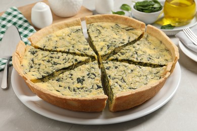 Photo of Plate of cut delicious spinach pie on light table, closeup
