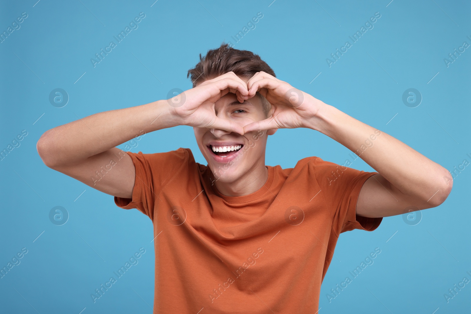 Photo of Happy man showing heart gesture with hands on light blue background