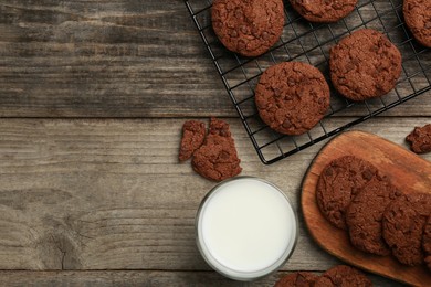 Photo of Delicious chocolate chip cookies and glass of milk on wooden table, flat lay. Space for text