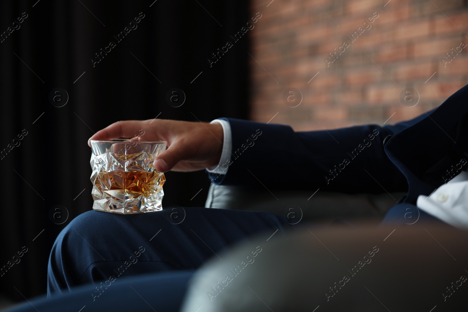 Photo of Young man with glass of whiskey indoors, closeup