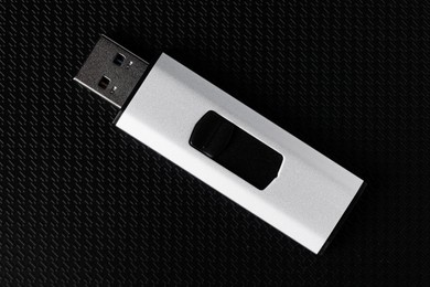 Photo of Modern usb flash drive on black textured background, top view