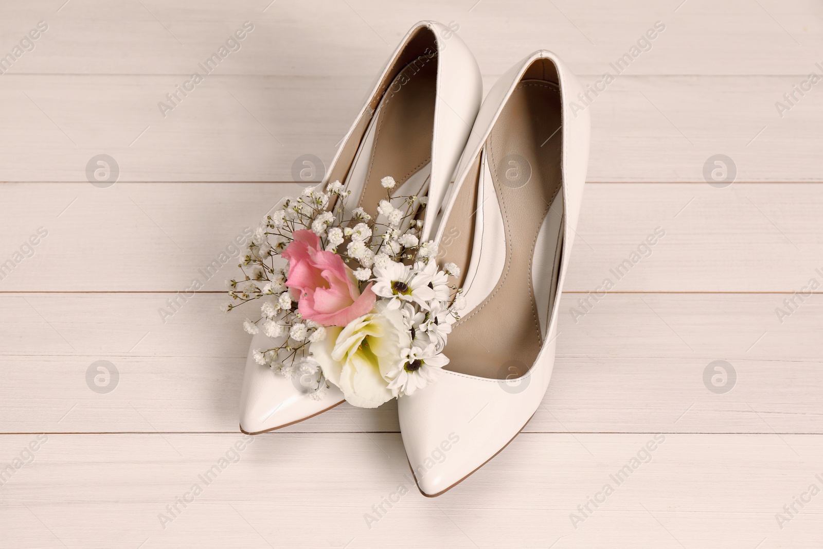 Photo of Women's shoes with beautiful flowers on beige wooden background