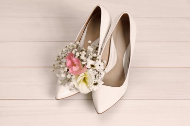 Photo of Women's shoes with beautiful flowers on beige wooden background