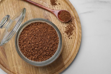 Jar of instant coffee and spoon on white marble table, top view