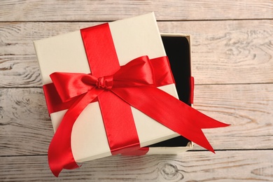 Elegant gift box with bow on wooden background, top view