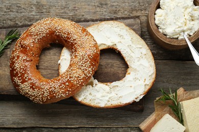 Photo of Delicious bagel with tofu cream cheese and rosemary on wooden table, flat lay