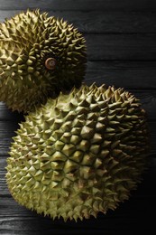 Photo of Ripe durians on black wooden table, closeup
