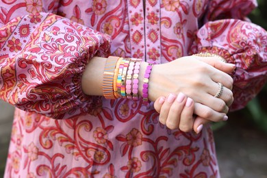 Photo of Woman wearing many stylish bracelets outdoors, closeup