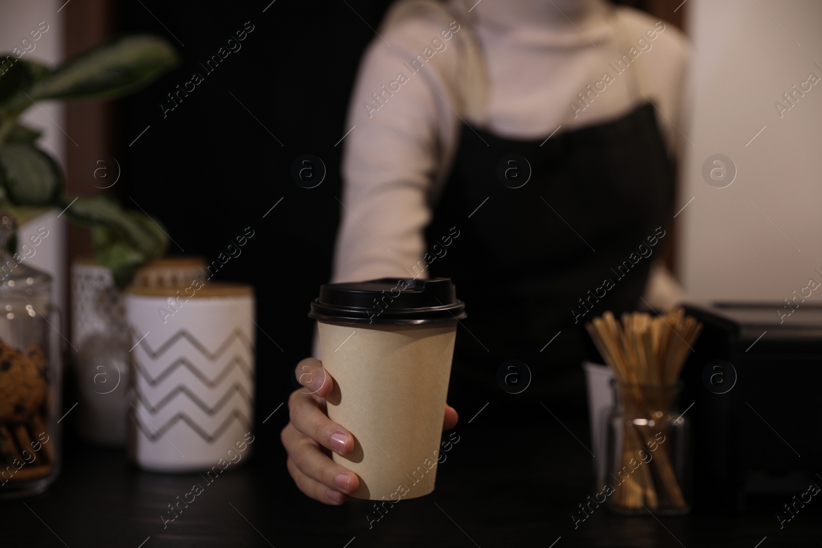 Photo of Barista putting takeaway coffee cup on table indoors, closeup