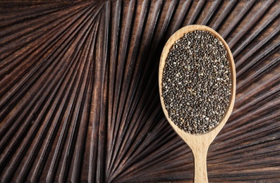 Photo of Spoon with chia seeds on wooden background, top view. Space for text