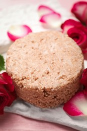 Photo of Solid shampoo bar and roses on pink wooden table, closeup. Hair care