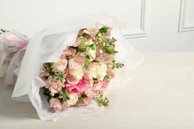 Beautiful bouquet of fresh flowers on wooden table near white wall, space for text