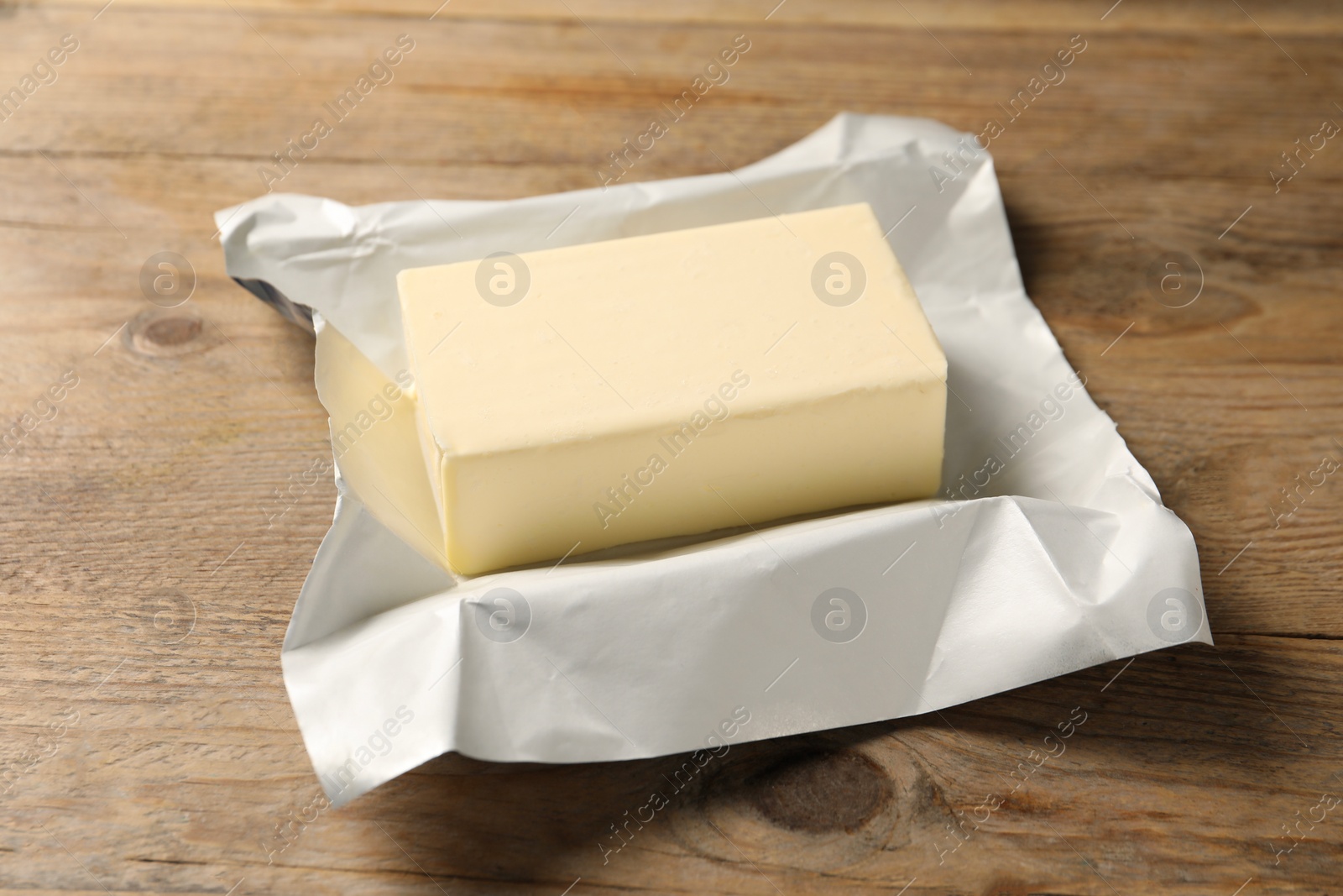 Photo of Block of tasty butter on wooden table