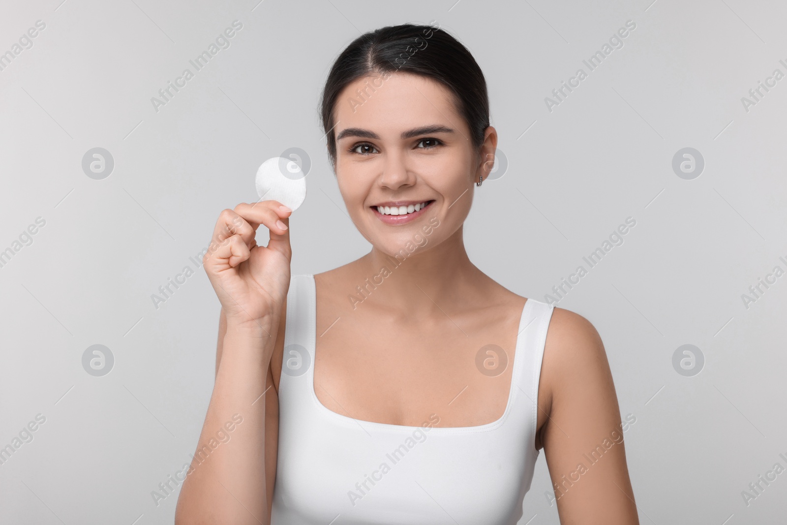 Photo of Young woman with cotton pad on light grey background