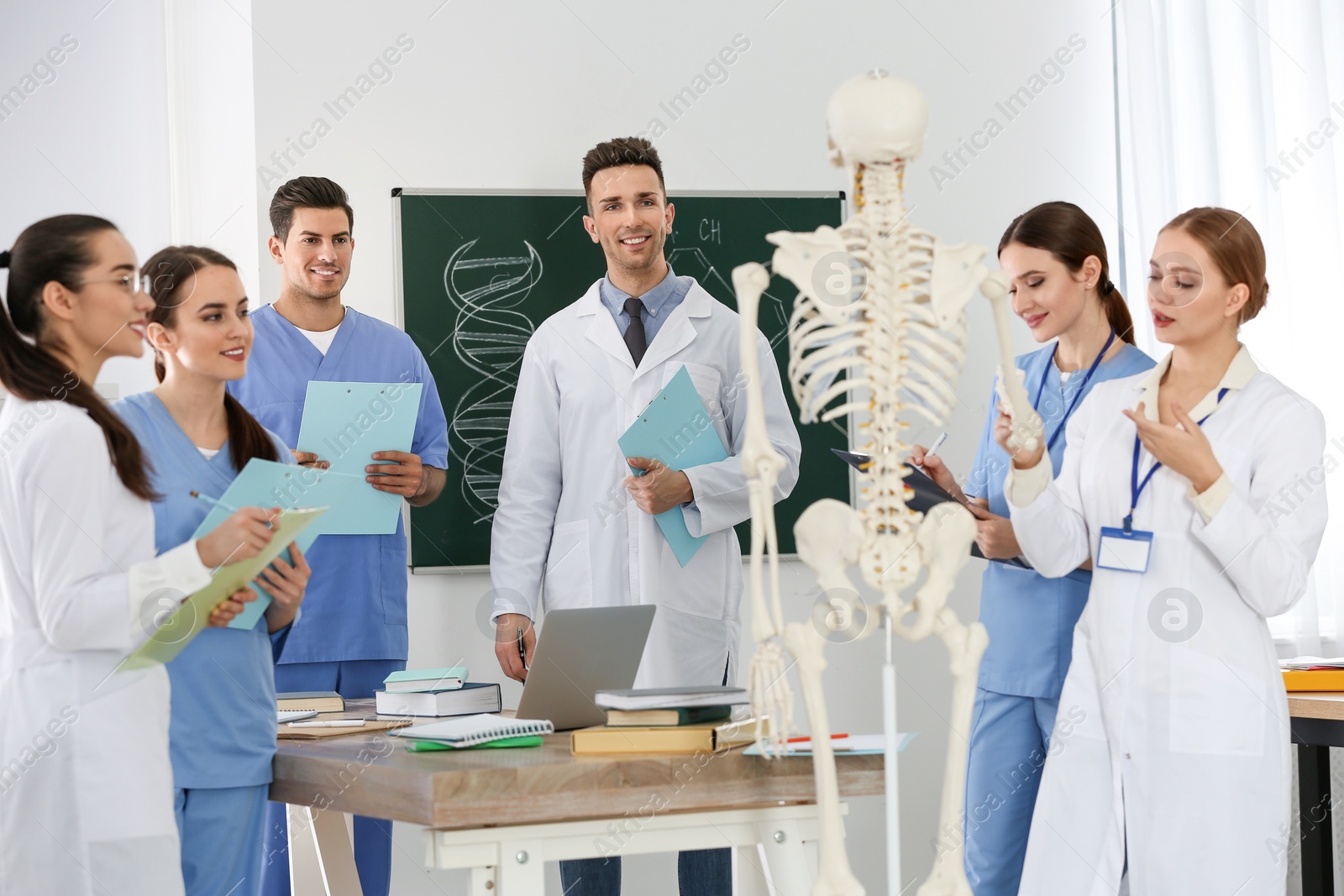 Photo of Medical students studying human skeleton anatomy in classroom