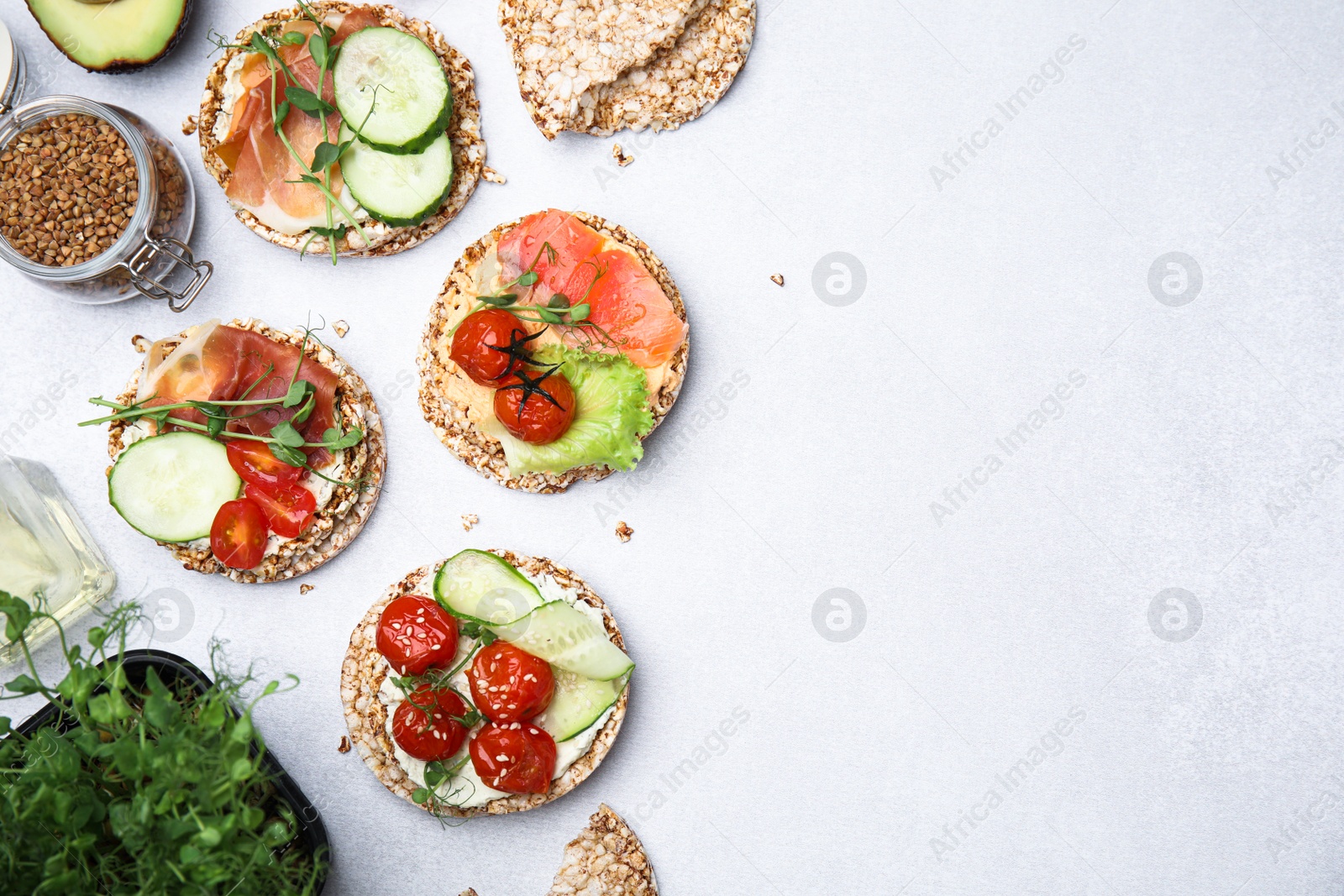 Photo of Set of crunchy buckwheat cakes with different ingredients on white background, flat lay. Space for text