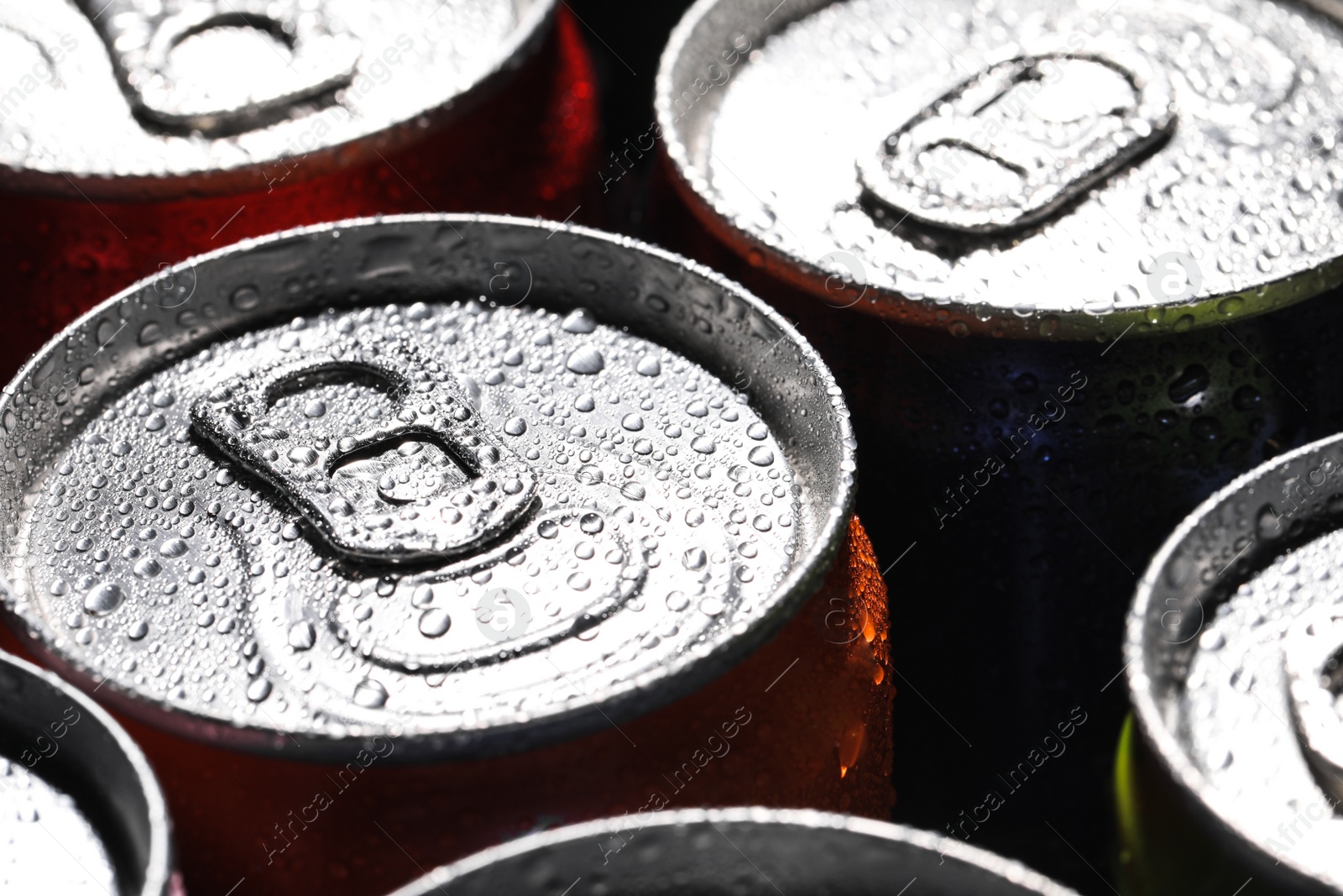 Photo of Aluminum cans of beverage covered with water drops as background, closeup