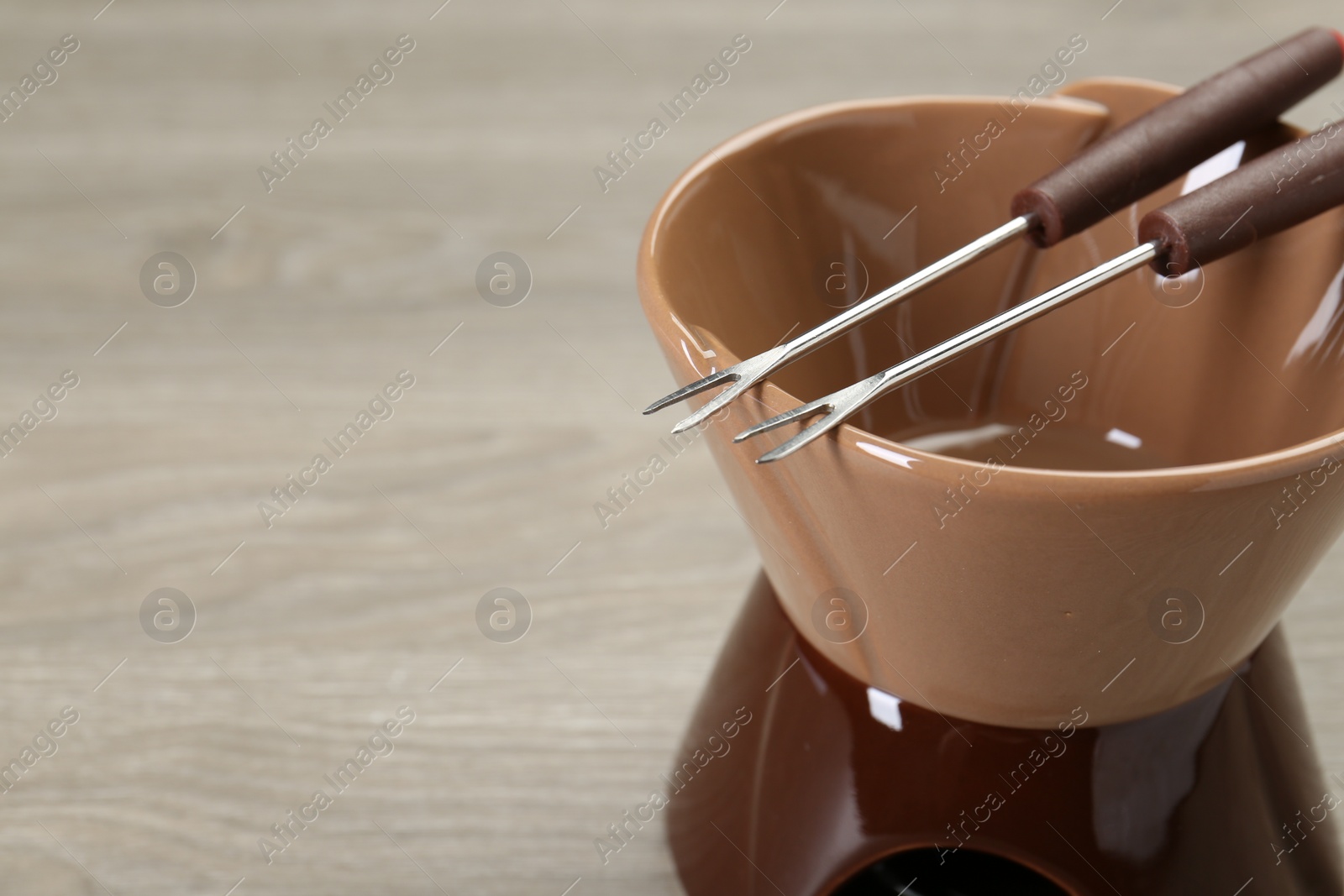 Photo of Fondue set on wooden table, closeup. Space for text