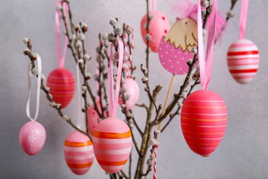 Beautiful willow branches with painted eggs on light grey background, closeup. Easter decor