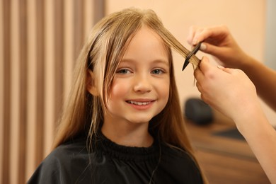 Photo of Professional hairdresser combing girl's hair in beauty salon