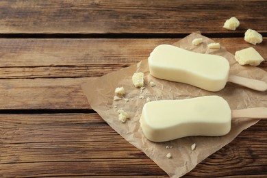 Photo of Glazed ice cream bars and white chocolate chunks on wooden table. Space for text