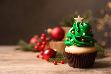 Photo of Christmas tree shaped cupcake on wooden table. Space for text