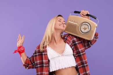 Happy hippie woman with retro radio receiver on purple background