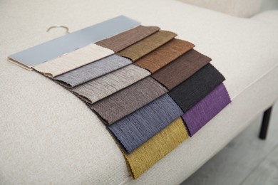 Photo of Catalog of colorful fabric samples on beige sofa, closeup