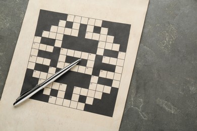 Blank crossword and pencil on grey table, top view. Space for text
