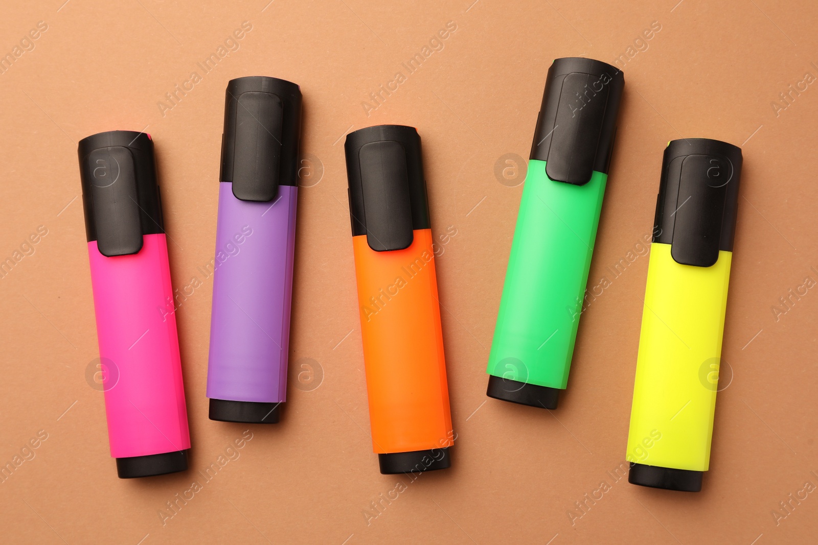 Photo of Bright color markers on pale orange background, flat lay